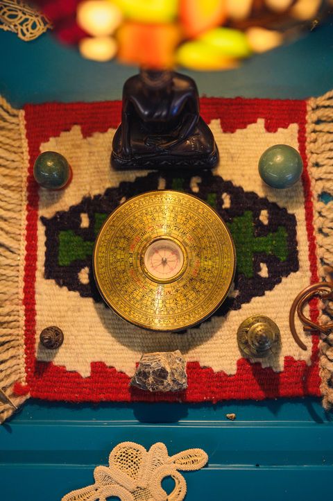 A golden feng shui compass on a woven rug, surrounded by crystals